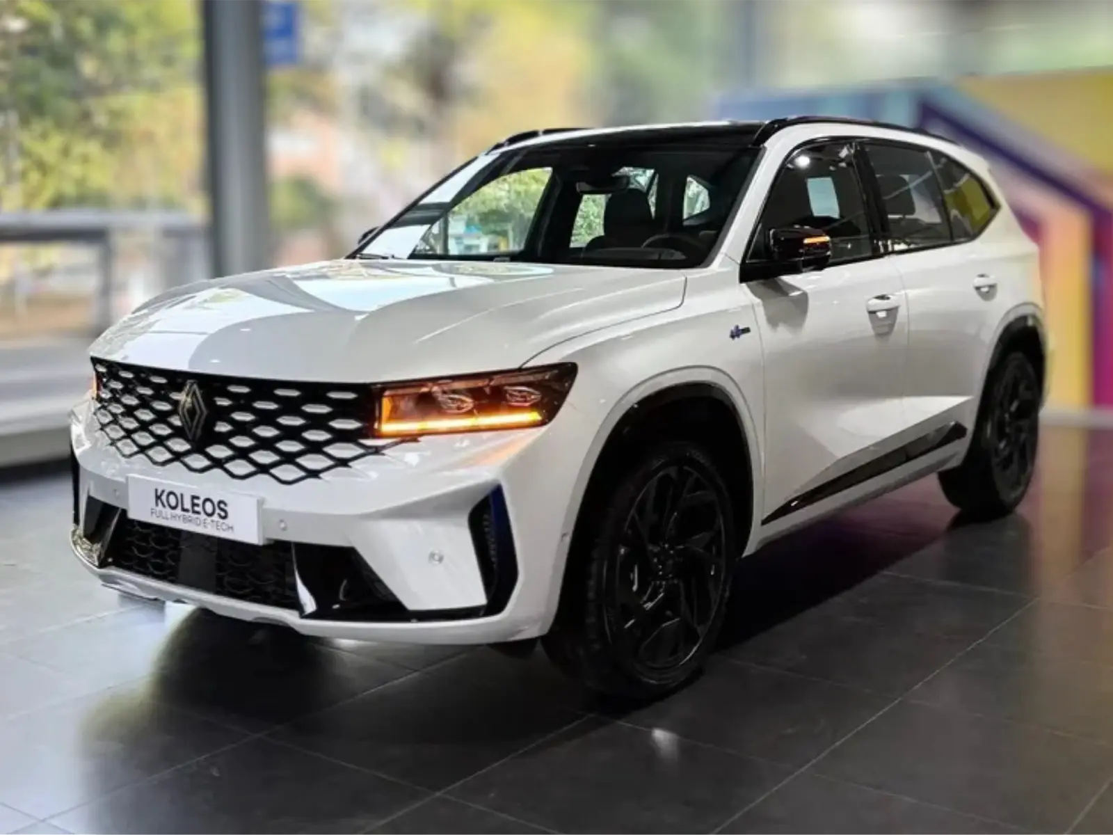 Renault Koleos E-Tech blanca en showroom, vista frontal 3/4
